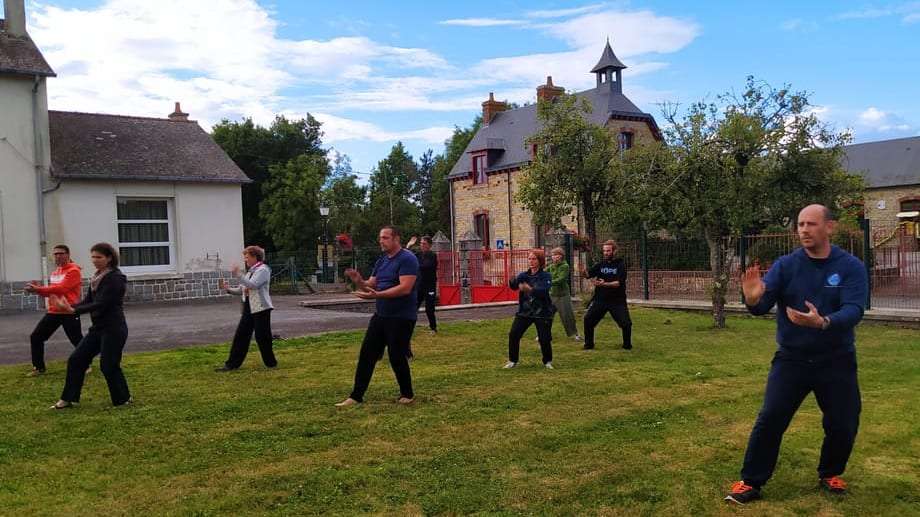 Groupe d'élèves pratiquant le Tai Chi Chuan et le Qi Gong en extérieur, en tenue souple et confortable